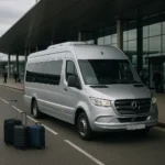 Silver executive minibus parked at kerb with luggage in foreground, ready for Heathrow airport transfer
