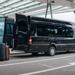 Executive minibus boot open showing large luggage compartment at Heathrow Airport terminal