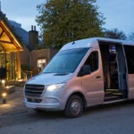 Executive minibus with professional driver parked at Heathrow Airport ready for group transfer