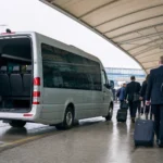 Executive minibus parked outside modern conference centre with business delegates boarding
